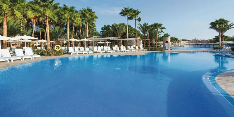 Pool and palm-shaded sun deck at Hotel Riu Cabo Verde, the adults-only all inclusive resort on the beach at Santa Maria, Sal, Cape Verde